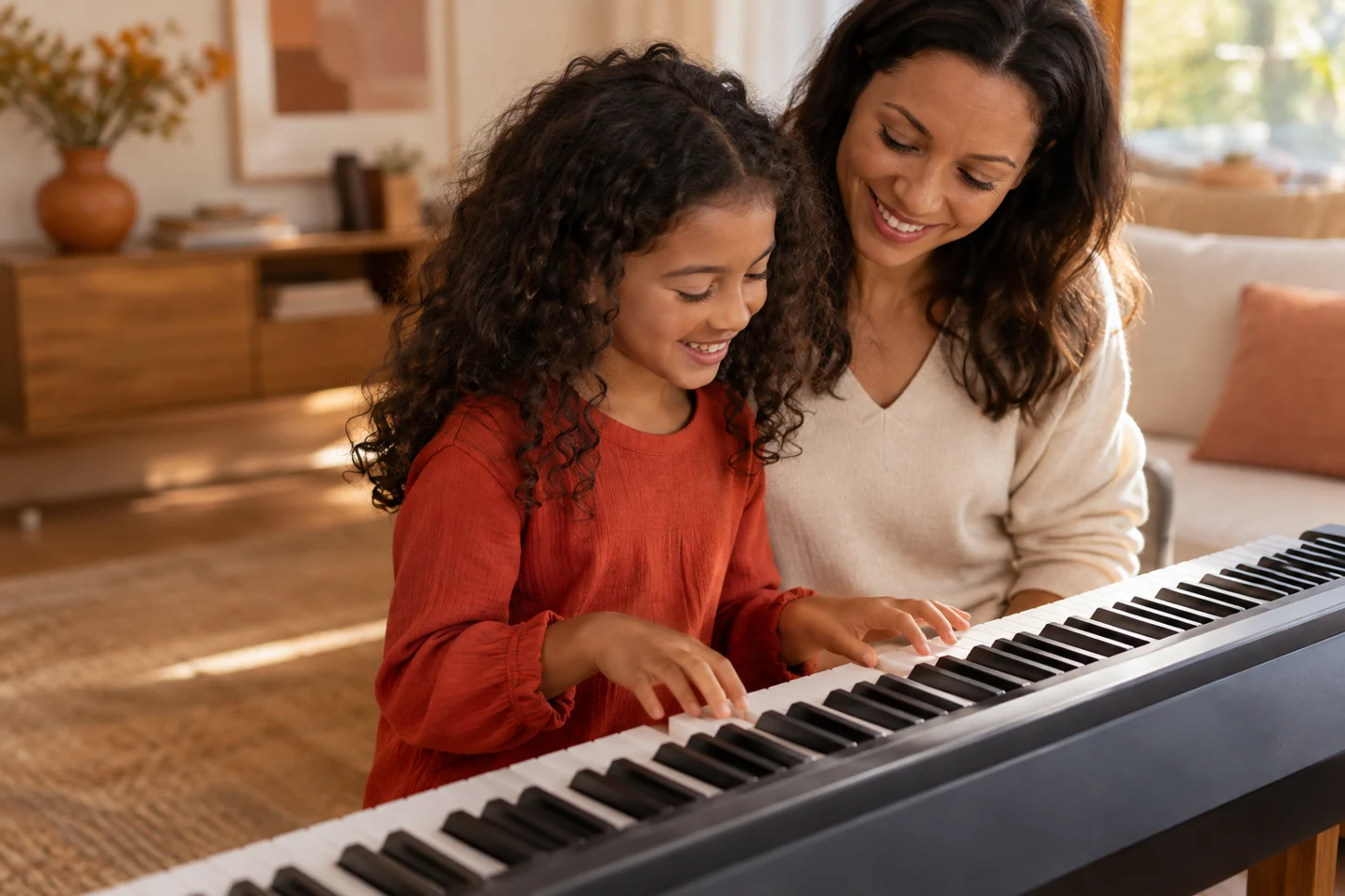A young girl playing piano with her mother beside her